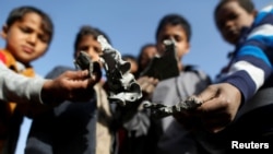 Boys hold missile shrapnel they collected from the site of a Saudi-led air strike in the Houthi-held capital Sanaa, Yemen, Jan. 20, 2019.