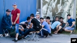 Rekan dan kerabat pekerja dari Kyrgyzstan yang menjadi korban kebakaran gudang percetakan di Moskow, Rusia, berkumpul di dekat lokasi musibah tesebut (27/8).