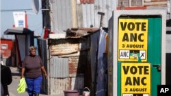 Une femme, à gauche, se promène près d’une affiche de campagne de l’ANC (African National Congress), lors des élections municipales dans le township de Khayelitsha à la périphérie de Cape Town, Afrique du Sud, 1 août 2016. 