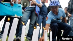 FILE - A local policeman offers flowers to the victims of the Manila bus hostage crisis in 2010 at the Luneta Park in Manila on August 23, 2013.