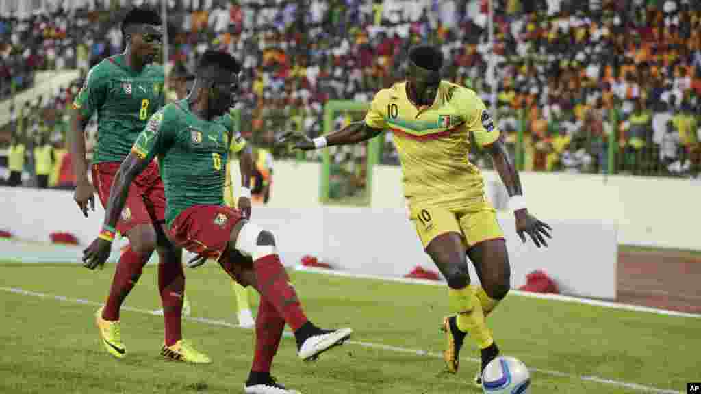Bakary Sako du Mali, à droite, est aux prises avec Benjamin Moukandjo du Cameroun, à gauche, et Ambroise Oyongo Bitolo, au cours de leur Coupe d'Afrique des Nations match de football du groupe D dans Estadio De Malabo, Guinée équatoriale, mardi 20 janvier 2015.