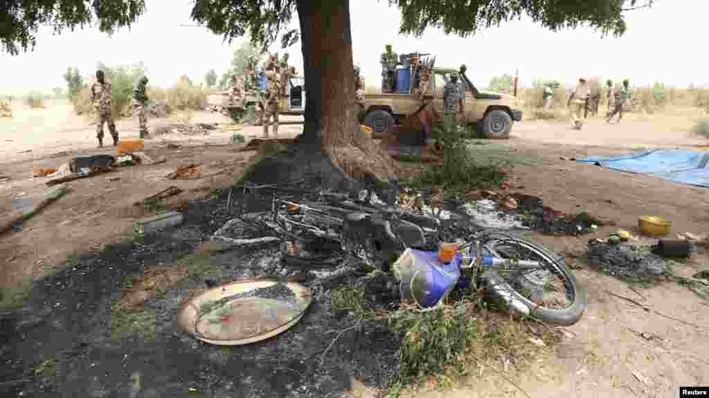 Des soldats tchadiens se tiennent à côté de ce qu'ils disent être un camp du groupe insurgé Boko Haram, que l'armée tchadienne dit avoir détruit dans la bataille de Gambaru, au Nigeria, le 26 février 2015.