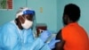 A health worker injects a woman with an Ebola vaccine during a trial in Monrovia, Feb. 2, 2015. 