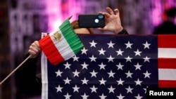 Seorang pengunjuk rasa memegang bendera Iran dan AS dalam konvensi warga AS keturunan Iran, di California, Los Angeles, California, 11 Januari 2020. (Foto: Patrick T. Fallon/Reuters)