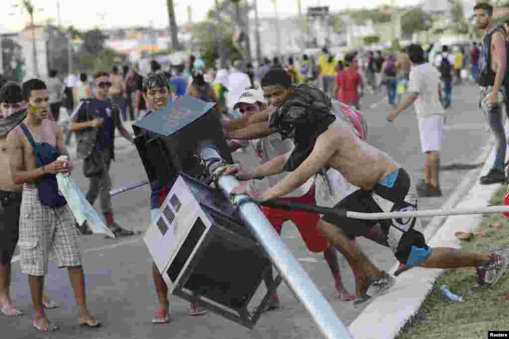 Demonstrators tear down a traffic light during clashes with riot police near the Estadio Castelao in Fortaleza, Brazil, June 19, 2013.