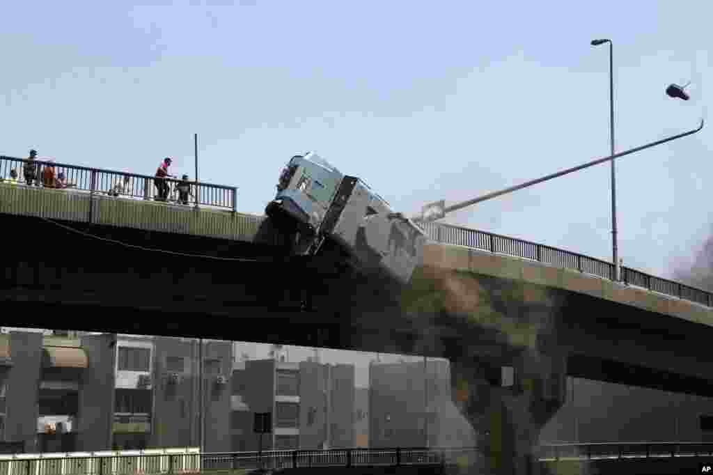 Sebuah kendaraan polisi didorong keluar dari jembatan '6 Oktober' oleh para pendukung Presiden terguling Mohamed Morsi di bagian Timur Nasr City, Kairo, Mesir.