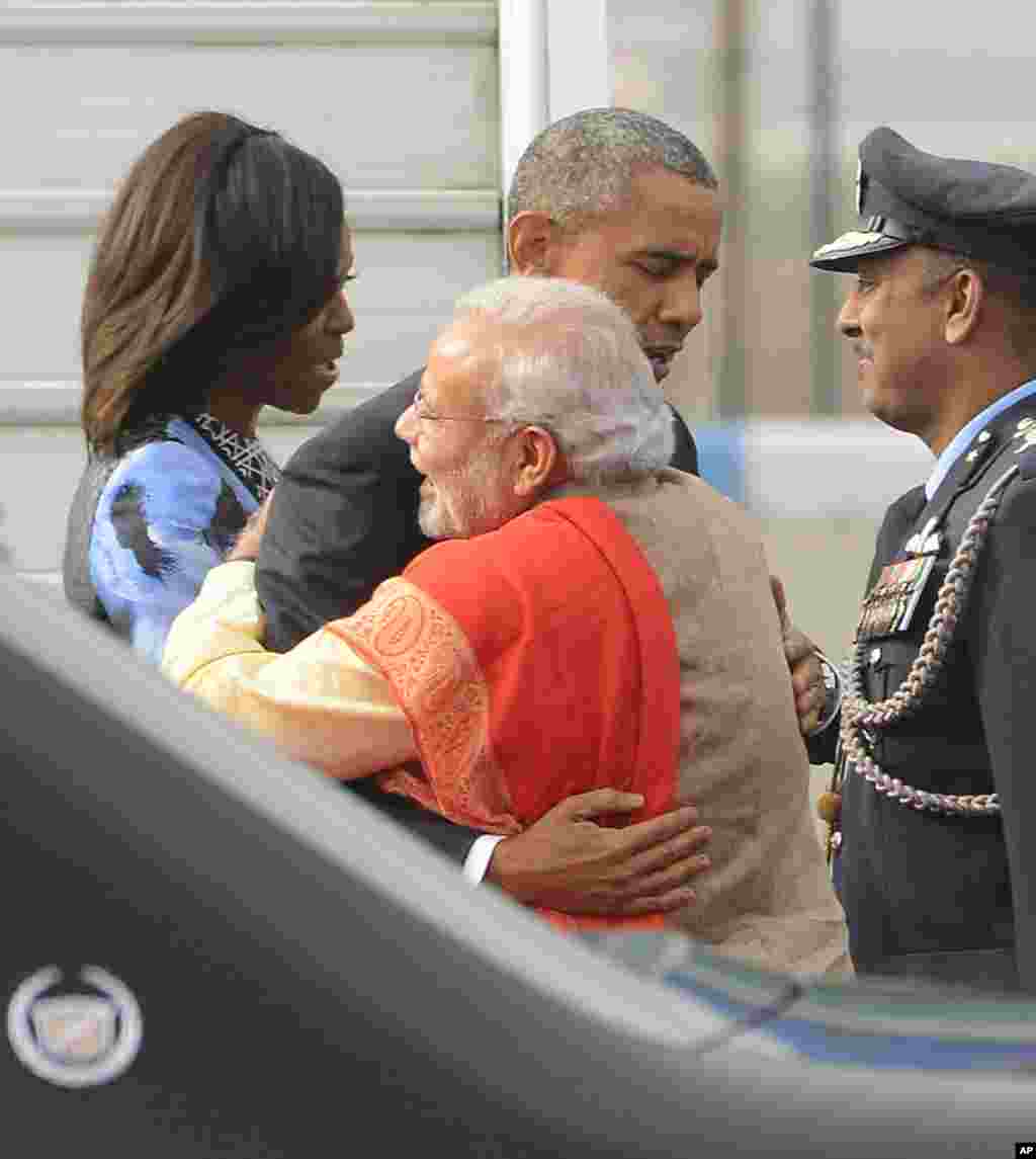 Indian Prime Minister Narendra Modi and U.S. President Barack Obama embrace, as first lady Michelle Obama speaks with an officer upon arrival at the Palam Air Force Station in New Delhi, India, Jan. 25, 2015.