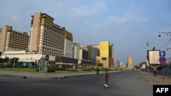 A boy in roller skates crosses a street in an area of the NagaWorld Casino buildings in Phnom Penh on March 25, 2021. (Photo by TANG CHHIN Sothy / AFP)