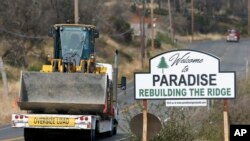 Vehicles pass a sign welcoming people to Paradise, Calif., Nov. 5, 2019. The sign also displays the slogan, "Rebuilding The Ridge," that has become the community's rallying cry since a wildfire devastated the area.