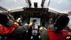 Pilot Angkatan Laut Indonesia Mayor Bambang Edi Saputro (kiri) dan Letnan Dua Tri Laksono memeriksa peta saat melakukan pencarian pesawat Boeing 777 milik Malaysia Airlines di perairan Indonesia (10/3). (AP/Binsar Bakkara)