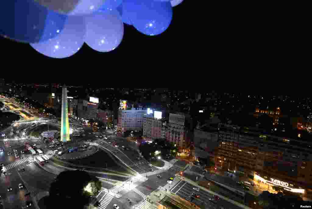 Obelisk disinari warna tim nasional brazil, kuning dan hijau, di Buenos Aires (10/6). Pada saat yang sama, Patung Kristus Penebus di Rio de Janeiro disinari warna putih dan biru dari tim nasional Argentina, untuk menunjukkan persaudaraan kedua negara. (Reuters/Enrique Marcarian)