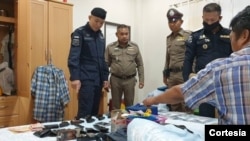 Uno de los sujetos arrestados por tráfico humano aparece sentado sobre su cama con varias armas de fuego, una muestra de lo peligroso de la industria pesquera en Tailandia.