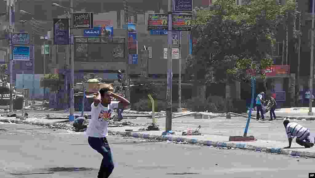 Seorang demonstran Mesir bereaksi setelah seorang pendukung presiden Mesir terguling Mohamed Morsi jatuh setelah ditembak pasukan keamanan. (AP/ Abdullah Shousha)