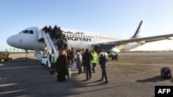 FILE - Passengers board an airplane at Mitiga International Airport, east of the Libyan capital Tripoli, December 12, 2019. 
