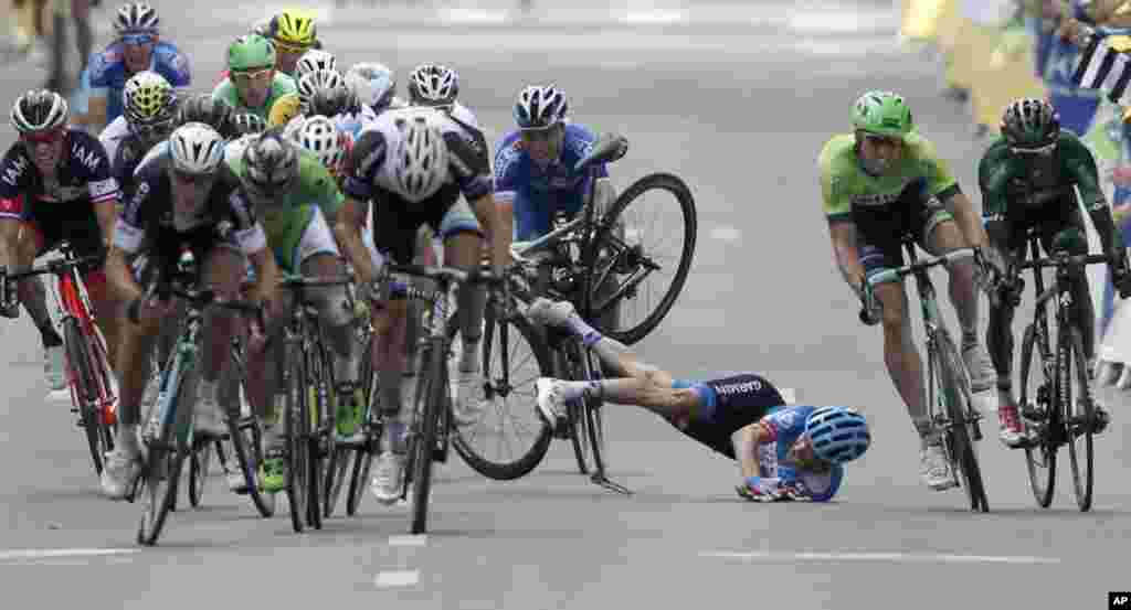 Andrew Talansky of the U.S. crashes as the pack with stage winner Italy's Matteo Trentin, foreground left, sprints towards the finish line during the 7th stage of the Tour de France.