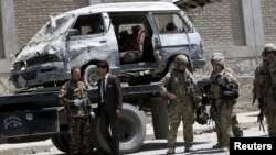 Afghan and foreign security forces keep watch at the site of car bomb attack in Kabul, May 17, 2015. 