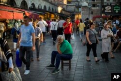 Seorang pria duduk di tengah pasar di Kota Istanbul, 18 Agustus 2022. Bank sentral Turki memangkas suku bunga acuan, meski laju inflasi meroket mendekati 80%. (Foto: Francisco Seco/AP Photo)