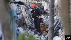 Petugas penyelamat mencari korban di antara reruntuhan gedung kondominium "Champlain Towers South Condo" di Surfside, Miami, Florida Kamis (24/6). 