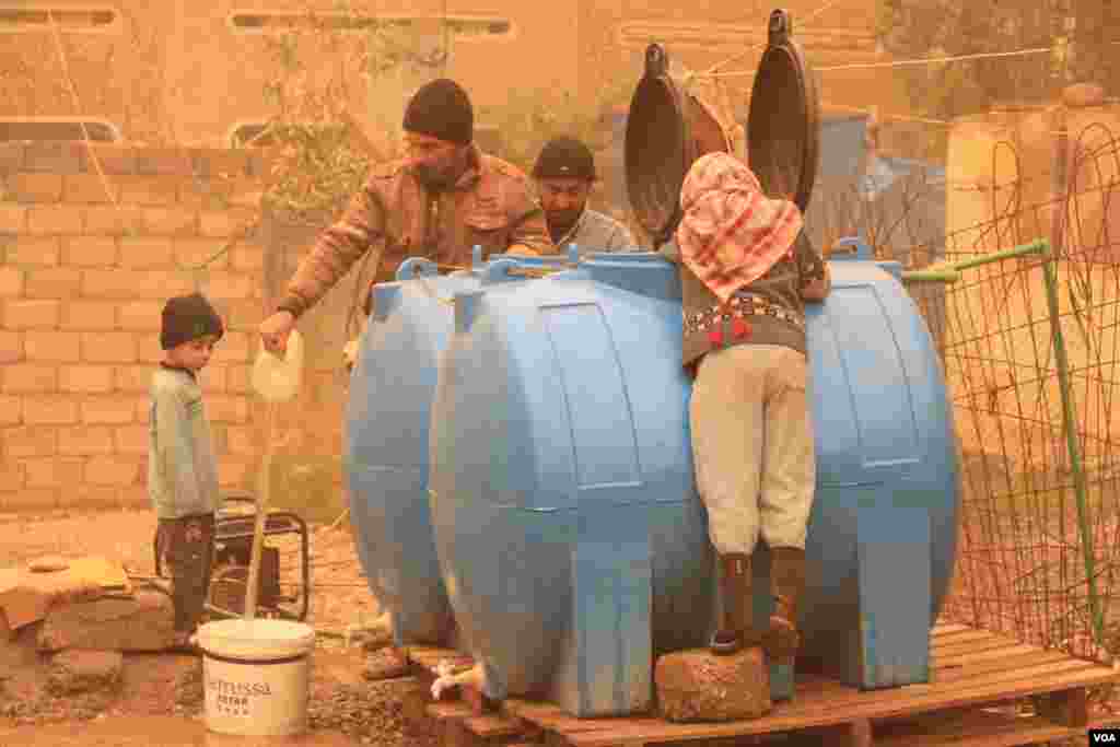 Families in Mosul gather water from a make-shift well they are operating with a generator because they have no running water or electricity on Dec. 2, 2016. (H.Murdock/VOA)