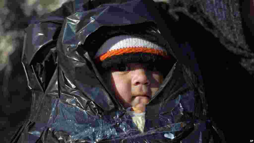 Couvert d’un plastique, un enfant voyage avec d’autres migrants à bord d’un canot à l'île grecque de Chios, en Turquie, 4 novembre 2015. 