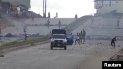 Des manifestants jettent des pierres sur un véhicule de la police anti-émeute sur une route principale du district de Sonfonia à Conakry, en Guinée, le 14 octobre 2019, sur cette image fixe tirée d'une vidéo. Reuters TV / via REUTERS