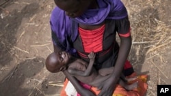 Adel Bol, 20 ans, berce sa fille de 10 mois, Akir Mayen, à Malualkuel dans la région de Bahr el Ghazal au Soudan du sud.