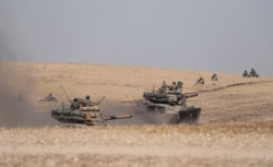 FILE - Turkish tanks and troops are stationed near Syrian town of Manbij, Syria, Oct. 15, 2019.