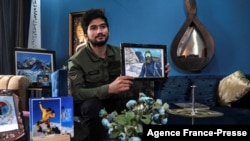 Pendaki gunung termuda Pakistan, Shehroze Kashif memegang potretnya selama wawancara dengan AFP di rumahnya di Lahore, 16 November 2021. (Arif ALI / AFP)