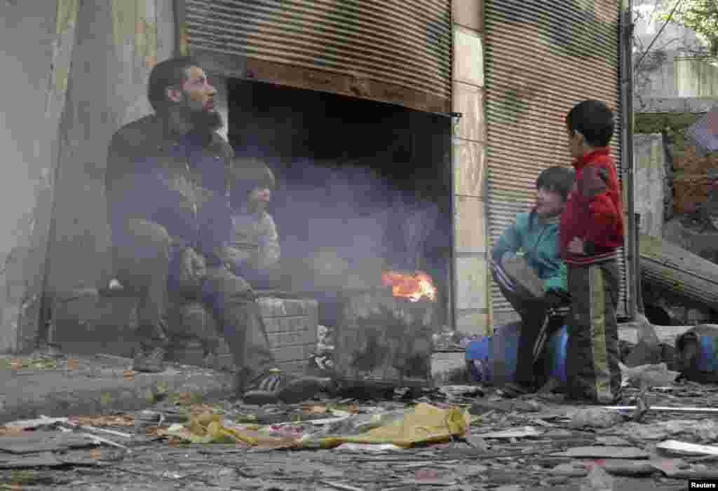 A man and children sit around a fire in the besieged area of Homs, Jan. 30, 2014.