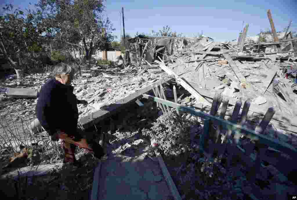 A woman checks damage at a destroyed home after shelling in the city of Donetsk, eastern Ukraine, Sept. 29, 2014.