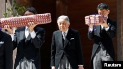 FILE - Japan's Emperor Akihito, flanked by Imperial Household Agency officials carrying two of the so-called Three Sacred Treasures of Japan, leaves the main sanctuary as he visits the Inner shrine of the Ise Jingu shrine, ahead of his abdication, in Ise, Japan, April 18, 2019. 