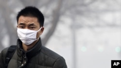 A man wears a mask as he walks to cross a street shrouded by haze in Beijing, China, Jan. 10, 2012.