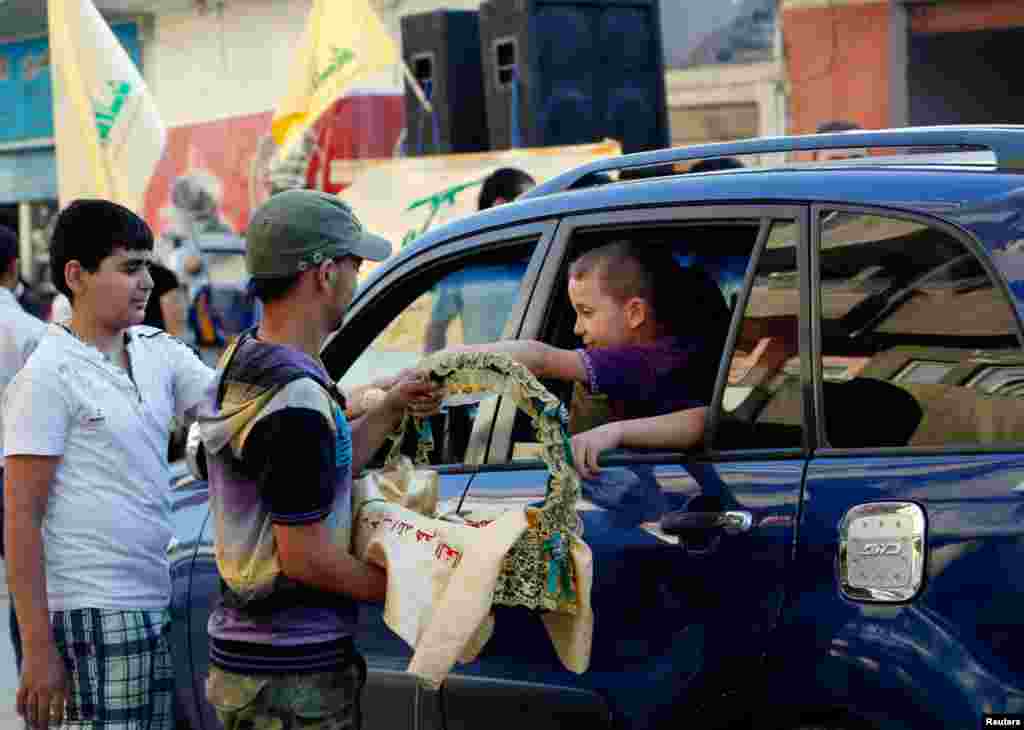 Supporters of Hezbollah distribute sweets as they celebrate after the Syrian army took control of Qusair with Hezbollah's support from rebel fighters, in the Shi'ite town of Hermel, Lebanon, June 5, 2013.