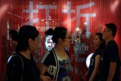 People walk by a fashion retailer having promotion sale at a shopping mall in Beijing, July 15, 2019.