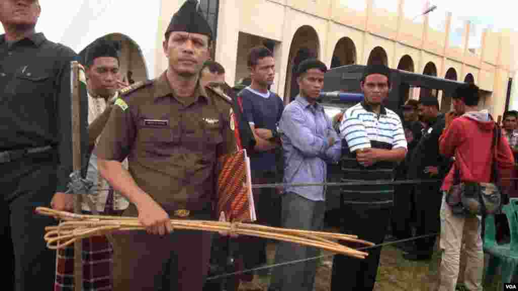 A policeman displays canes used to whip convicted criminals under Aceh's Shariah law, Dec. 5, 2014. (Maimun Saleh/VOA)