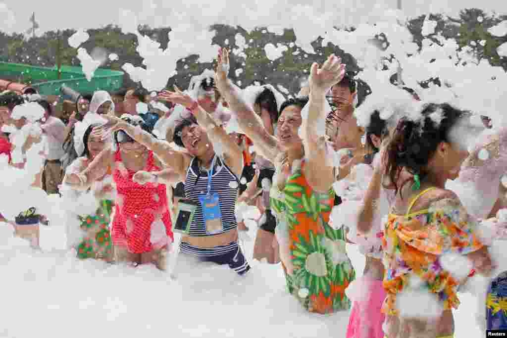 Para pengunjung bermain busa di "water park" kota Yantai, Shandong, China.