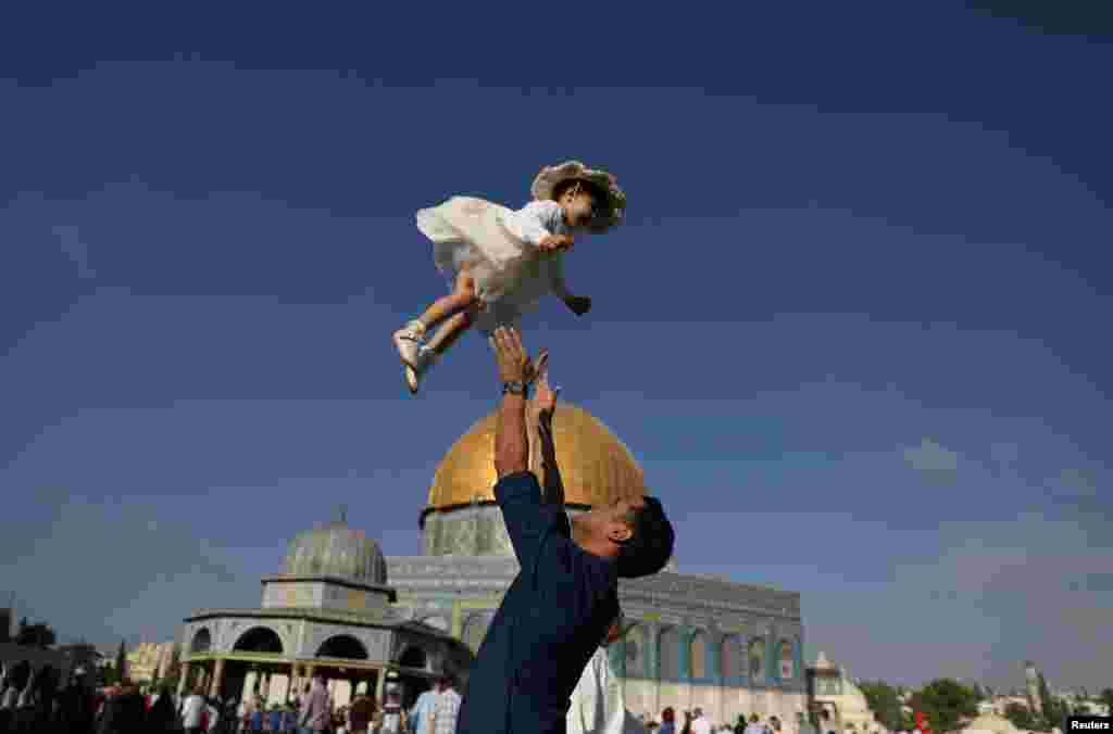 A Palestinian man throws his child in the air following morning prayers marking the first day of Eid al-Adha celebrations, on the compound known to Muslims as al-Haram al-Sharif and to Jews as Temple Mount, in Jerusalem's Old City.