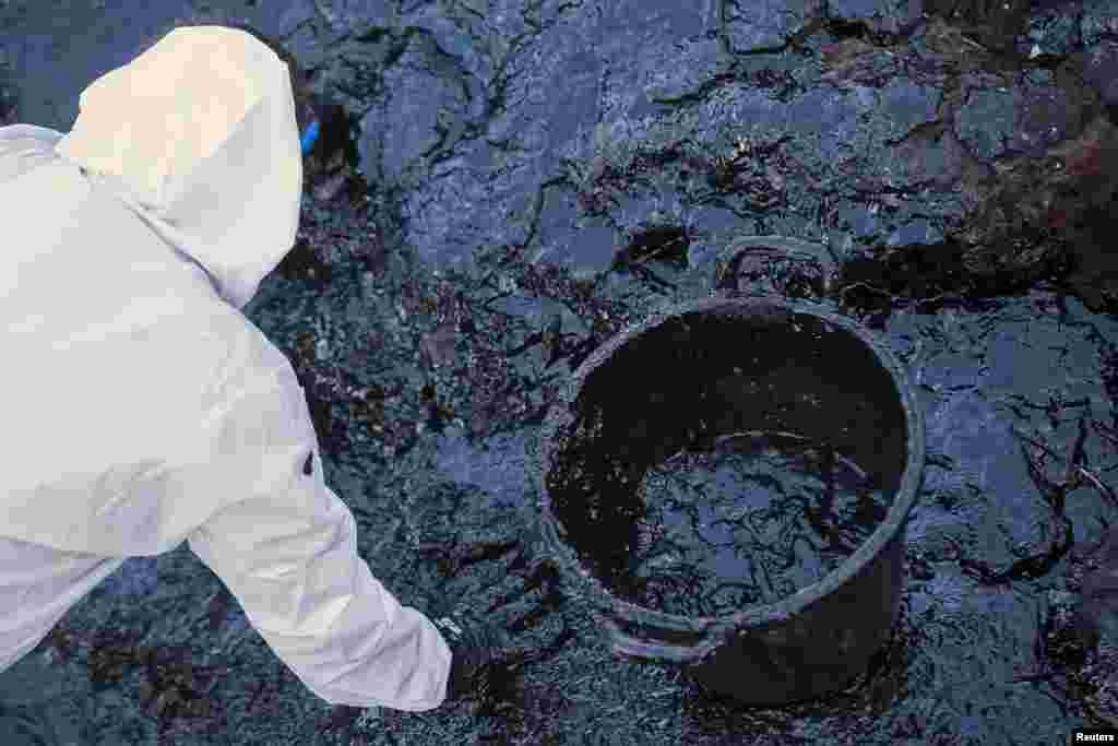 A worker cleans rocks stained by an oil spill at Cabron beach, in Spain's Canary Island of Gran Canaria, July 16, 2014. The origin of the oil spill is still unknown.