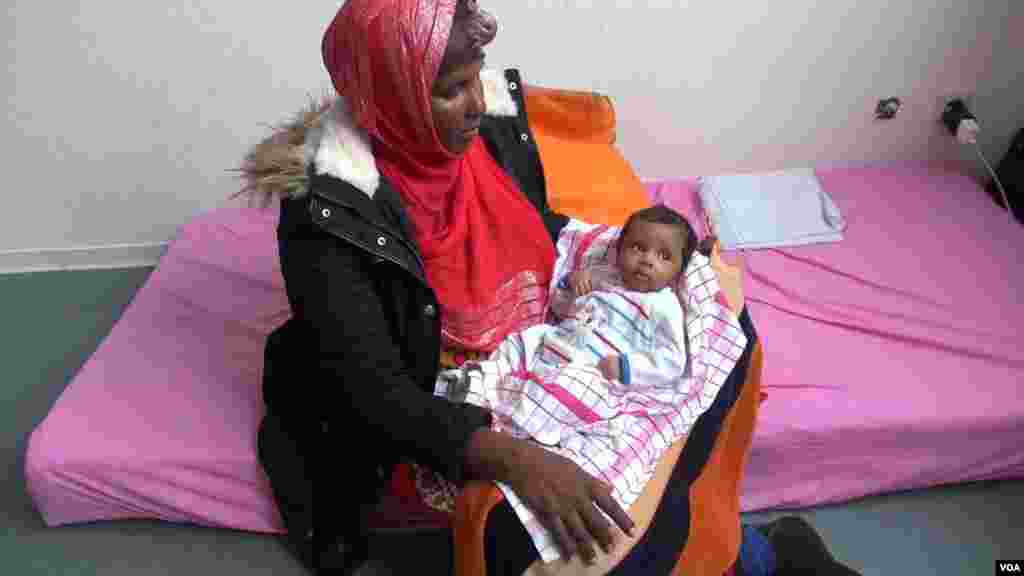 Abukar Ali Rahma, migrante, porte dans ses bras sa petite fille, Sophhia, attendant la réponse à sa demande d’asile, dans un centre de réfugiés près de Düsseldorf, Allemagne, octobre 2015. (A. Osman / VOA)