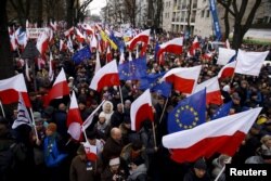 People hold European Union and Polish national flags during an anti-government demonstration in front of the Constitutional Court in Warsaw, Poland, Dec. 12, 2015.