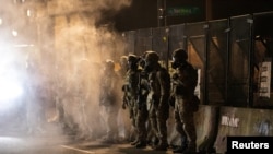 Un grupo de agentes custodia la corte federal de Justicia en Portland después de disparar gases lacrimógenos a los manifestantes el 29 de julio de 2020, al amanecer.