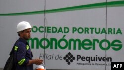 ARCHIVO - Un trabajador camina junto a un cartel de la empresa venezolana de fertilizantes Monómeros, en Barranquilla, Colombia, el 9 de octubre de 2021. AFP