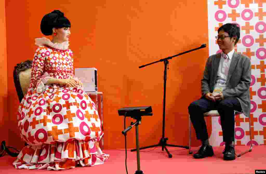 A visitor talks with the android robot 'totto', which was modeled form Japanese TV personality Tetsuko Kuroyanagi, during its demonstration at World Robot Summit in Tokyo.