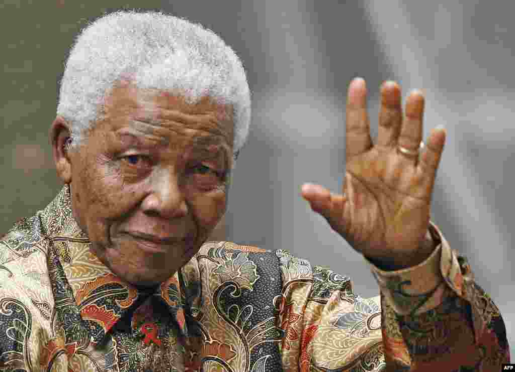FILE - Former South African President Nelson Mandela waves to the media as he arrives outside 10 Downing Street, in central London, 28 August 2007.