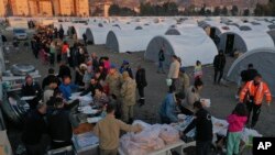 Para penyintas gempa yang kehilangan rumah, berbaris untuk menerima makanan di kamp darurat, di kota Iskenderun, Turki selatan, Selasa, 14 Februari 2023. (AP/Hussein Malla)