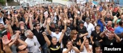 Members of the civil police and relatives of military police raise their arms in support of the police strike in front of a military police headquarters in Vitoria, Brazil, Feb. 8, 2017.