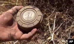 Seorang relawan pembersih ranjau mengambil sebuah ranjau darat di Daraa, Suriah, dalam foto yang diambil dari rekaman video, 7 September 2015. Foto dirilis oleh Pusat Pembersihan Ranjau dan Rehabilitasi Suriah.