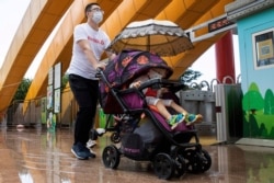 Un hombre y un niño usando mascarillas sanitarias visitan un parque local en Beijing, el sábado 23 de mayo de 2020.