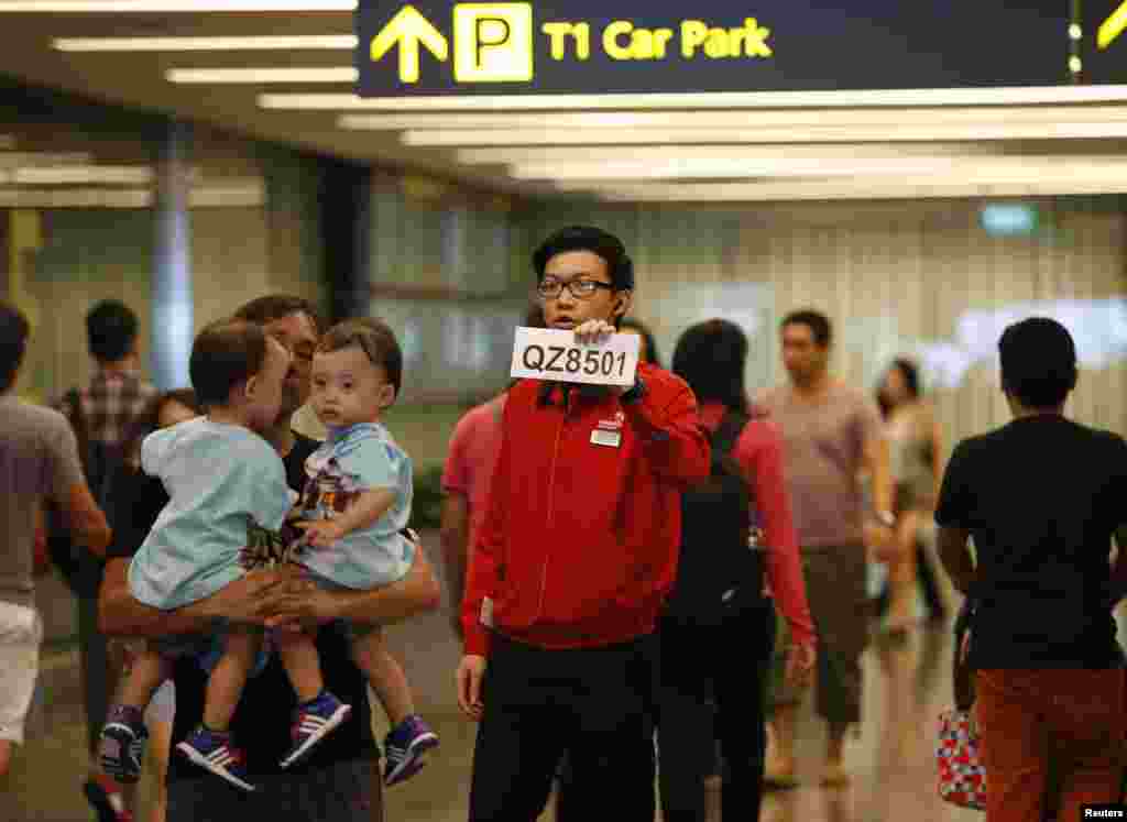 A Changi Airport staff holds up a sign to direct possible next-of-kins of passengers of AirAsia flight QZ 8501 from Indonesian city of Surabaya to Singapore, at Changi Airport in Singapore, Dec. 28, 2014.