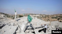 Bendera Hamas berkibar di atas puing-puing rumah Hussam Kawasme, salah seorang warga Palestina yang dicurigai menculik dan membunuh tiga remaja Israel pada Juni di kota Hebron, Tepi Barat (18/8).